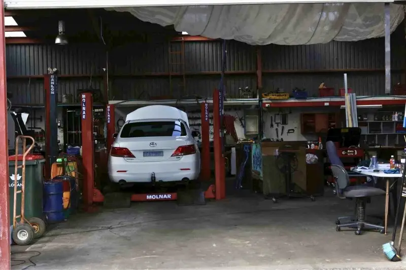 Car on lift in auto repair shop.