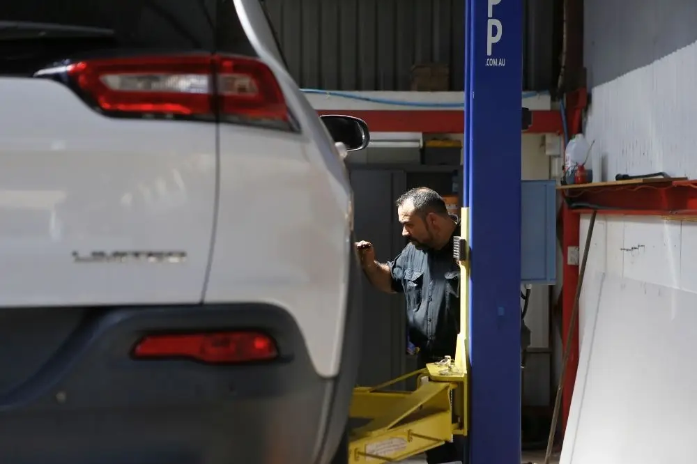 Mechanic inspecting vehicle on lift in garage.