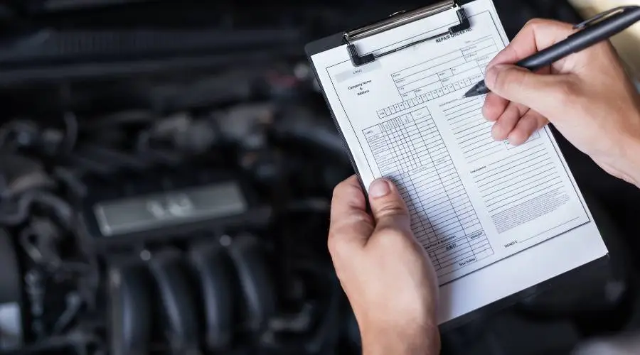 Licensed roadworthy inspector examining vehicle brakes during safety certificate inspection