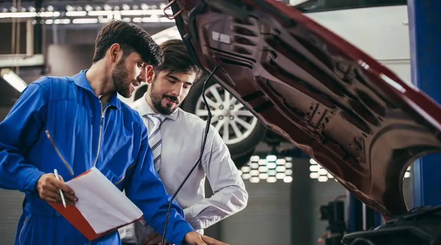 Professional mechanic performing logbook service following manufacturer specifications with service book