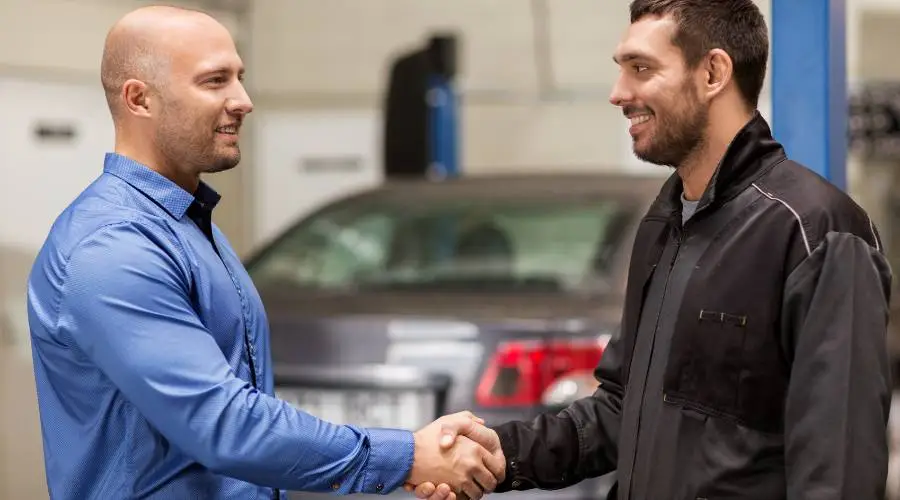 Customer receiving logbook service completion documentation from qualified mechanic warranty protection