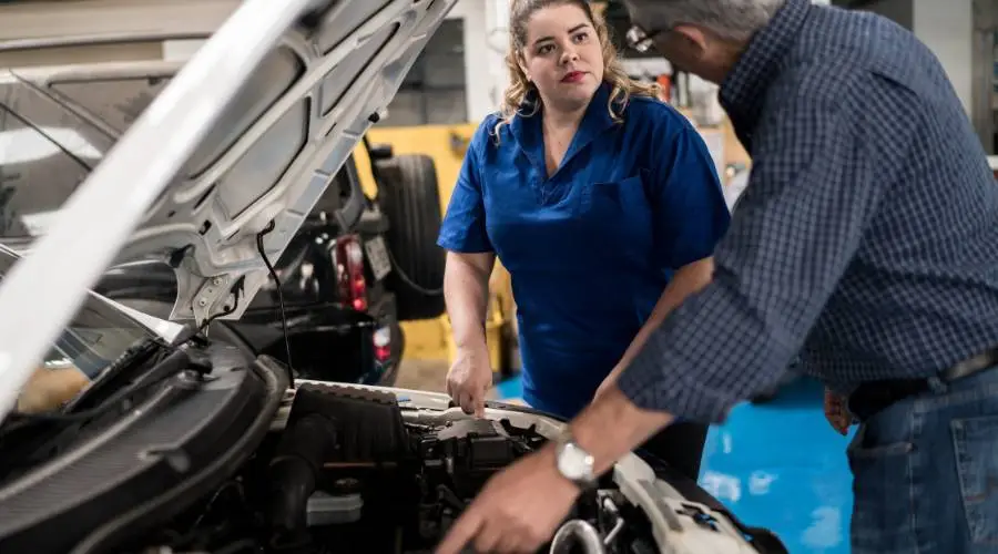 Professional mechanic explaining diagnostic results and warning signs to customer automotive repair consultation
