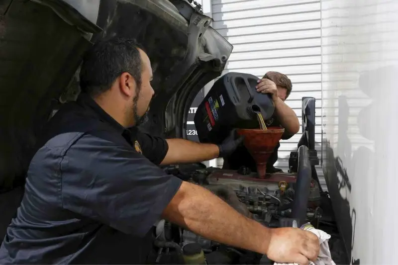 Mechanics changing engine oil of a truck