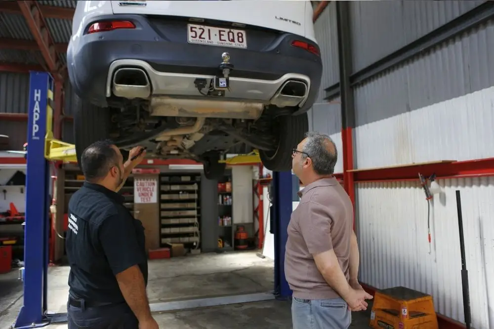 Mechanic inspecting lifted car in garage.