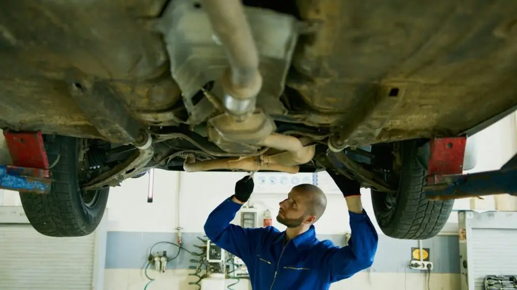 Mechanic inspecting car underside on lift.