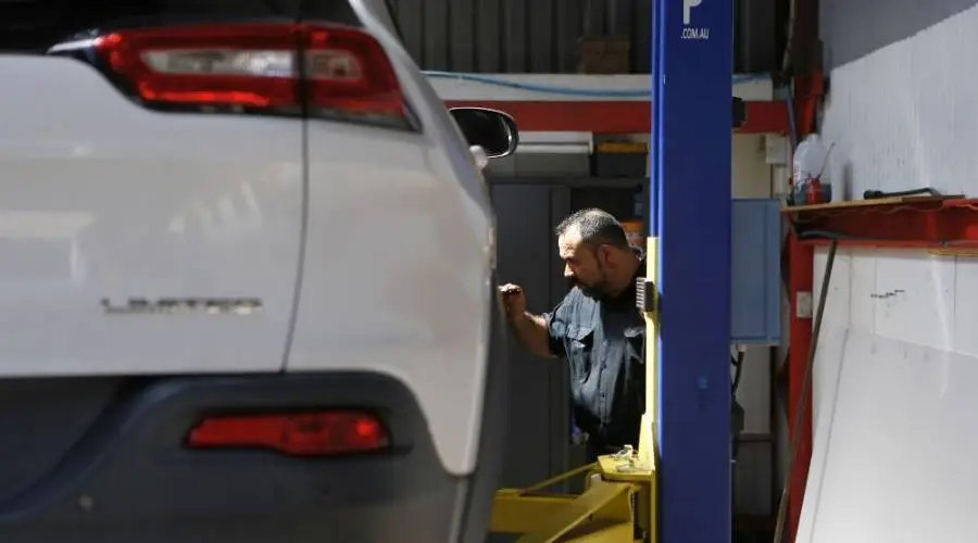 Mechanic inspecting car on lift in garage