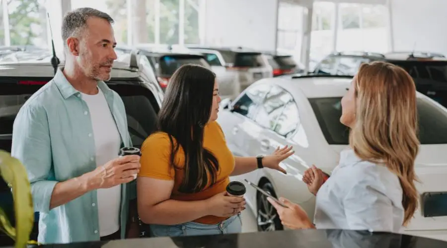 Couple discussing with car dealership employee.