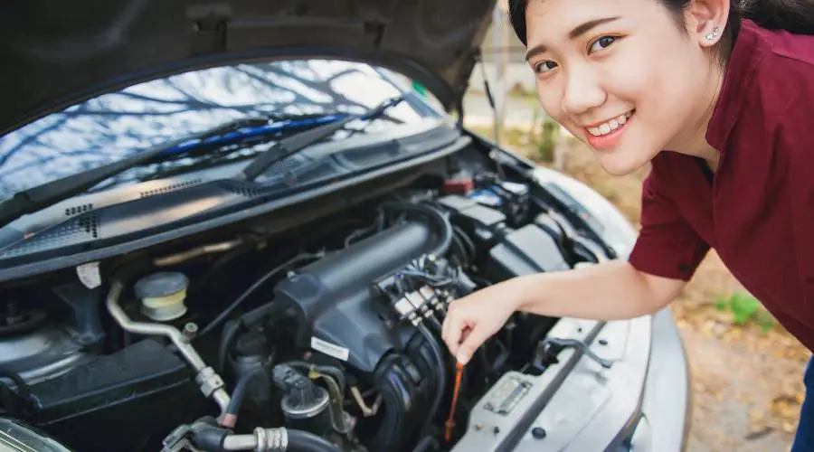 Person checking car engine oil level.