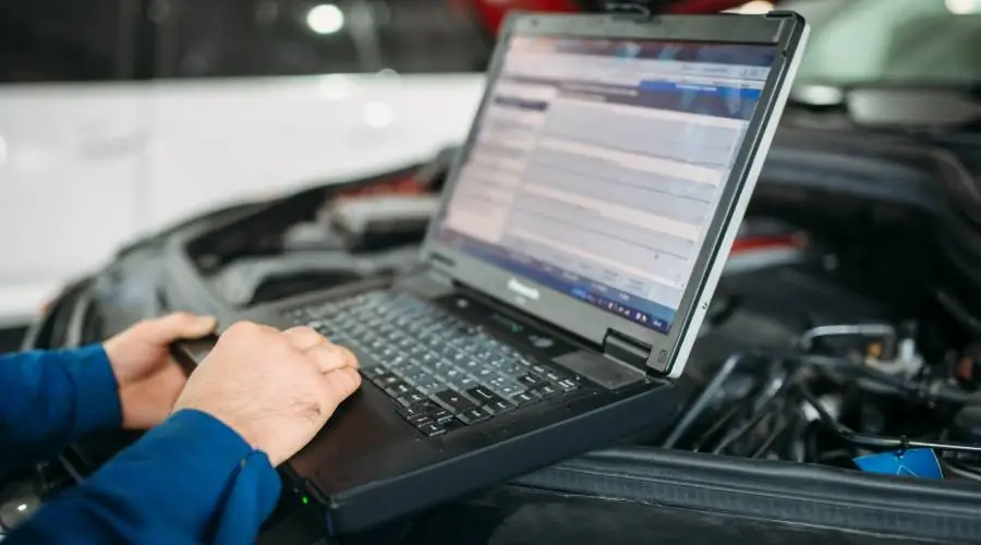 Mechanic using laptop for car diagnostics.