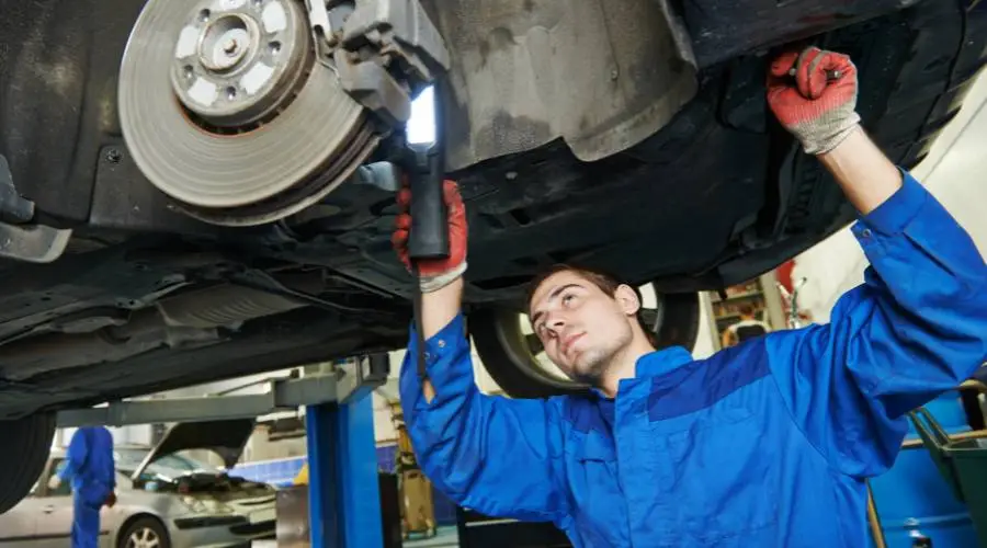Mechanic inspecting car brake system for repairs.