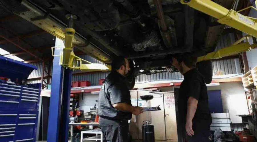 Mechanics inspecting vehicle on lift in garage.
